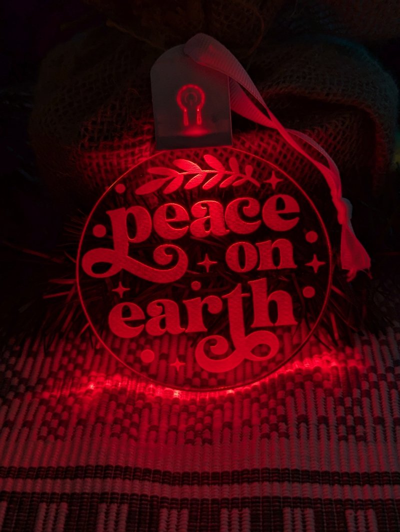 Laser-engraved Peace on Earth acrylic bauble displaying multi-colour LED lighting