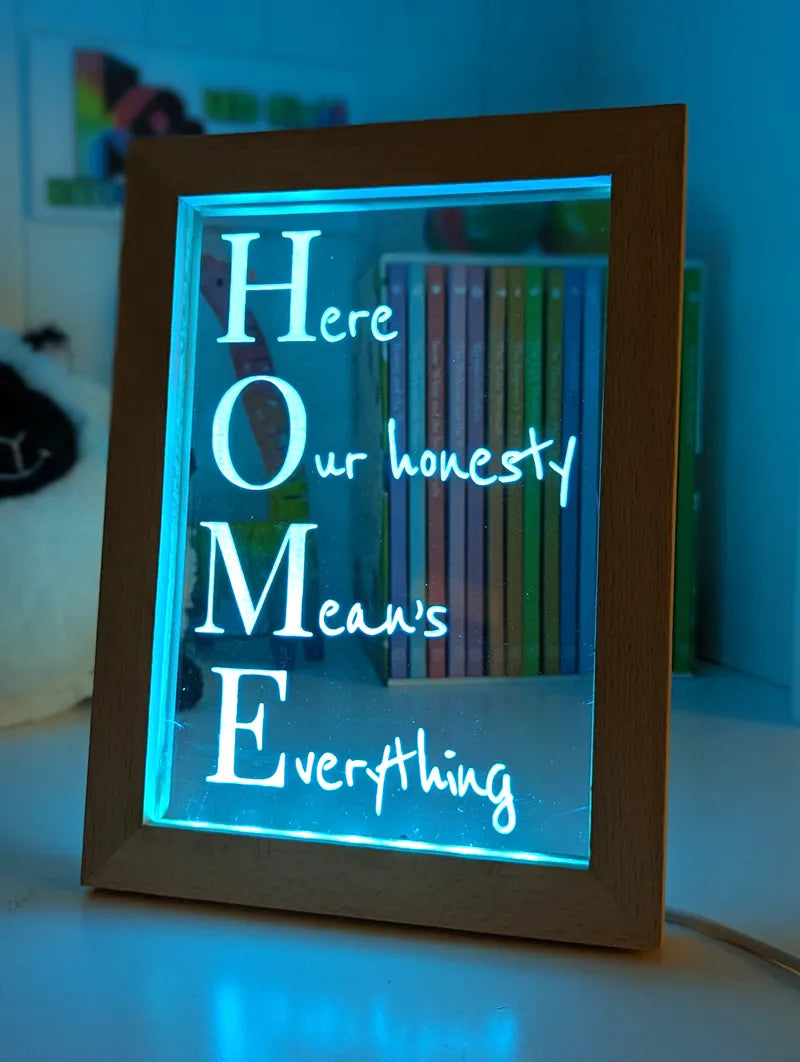 Decorative sign with 'Home Means Everything' text in a wooden frame with glowing blue light.